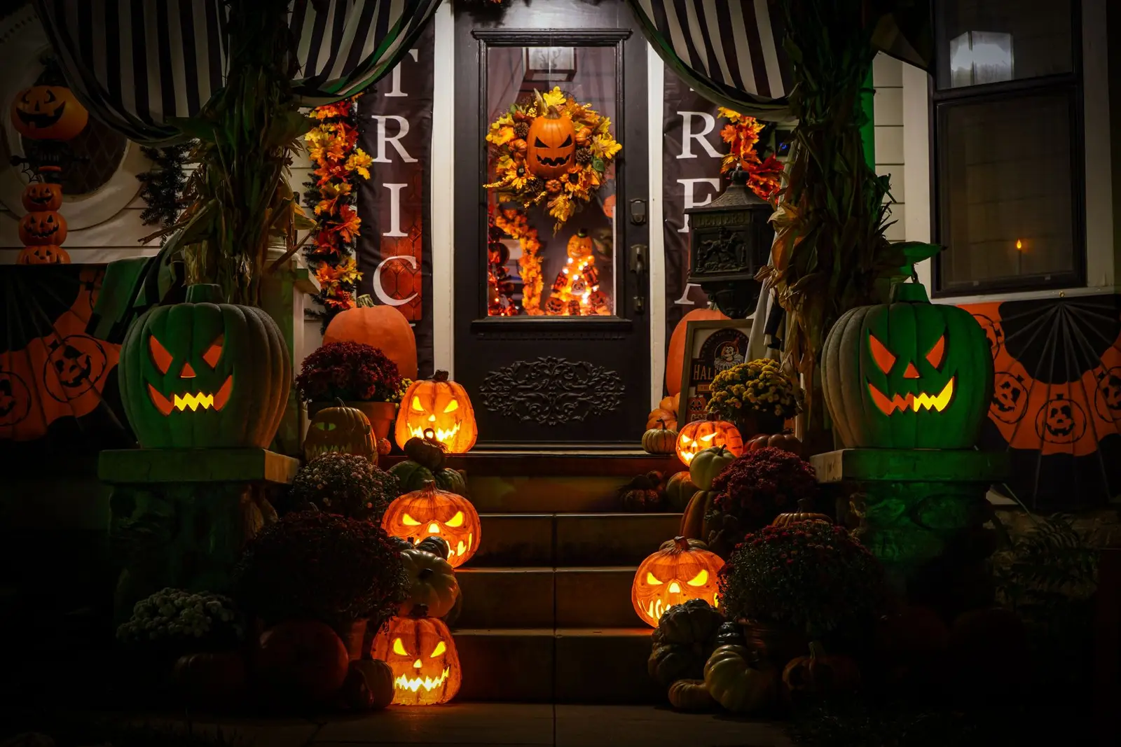 Front porch decorated with orange lights and glowing jack-o’-lanterns on the steps