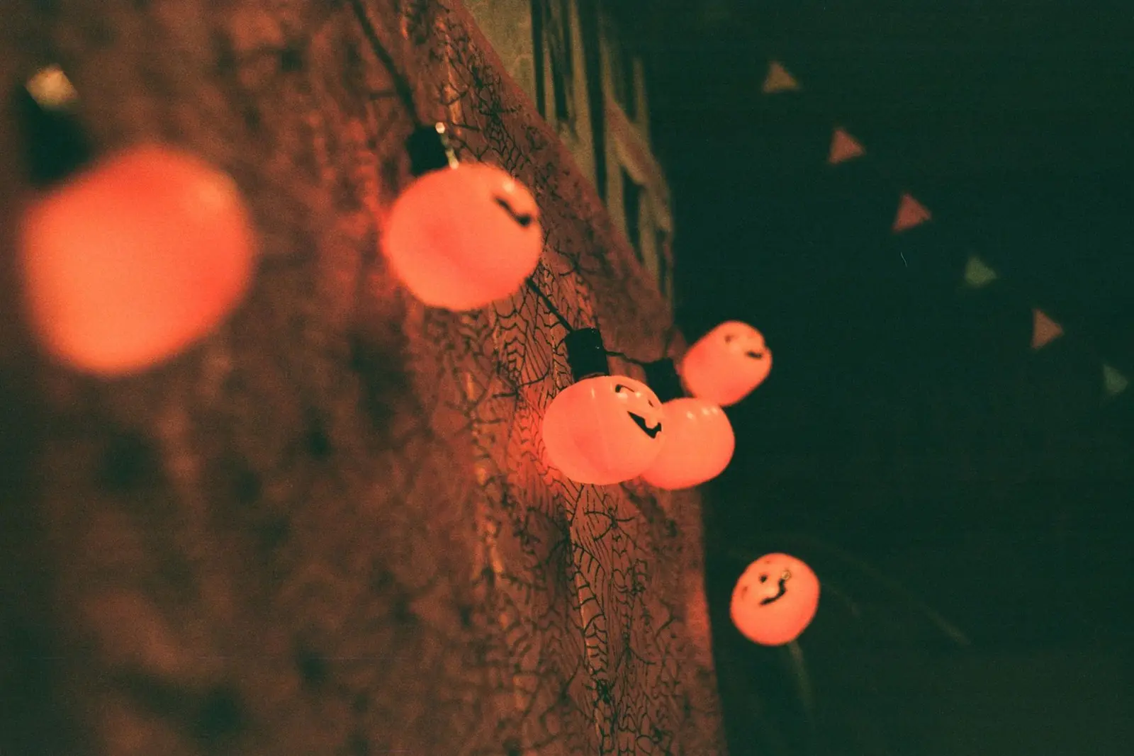 Pumpkin-shaped orange string lights hanging along a wall at night